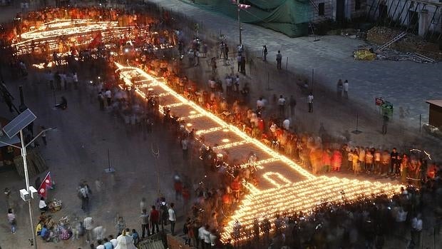 Vigilia celebrada ayer en Katmandú, recordando un año después del terremoto la Torre Dharhara y el templo Kasthamand, dibujados con velas, destruidos por el seísmo que causó la muerte de 9.000 personas