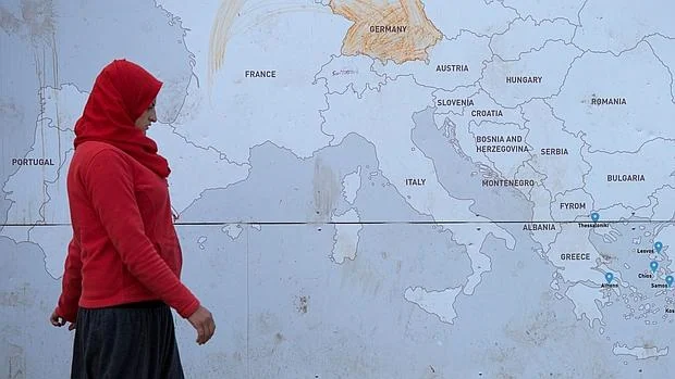 Una mujer pasa junto a un mapa de Europa en el campo de refugiados de Idomeni, en la frontera de Grecia y Macedonia