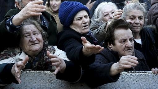 Un grupo de mujeres intenta hacerse con los productos regalados por agricultores que protestan contra los recortes de las pensiones en Atenas