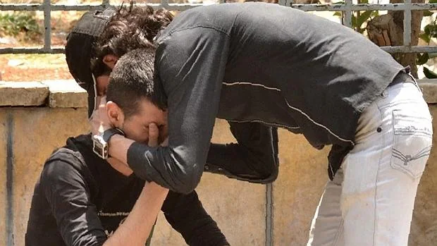 Un hombre sirio es consolado tras el bombardeo en una zona controlada por el Gobierno en Alepo