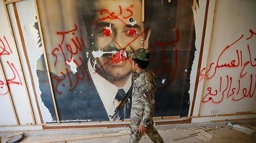 Un soldado iraquí observa un retrato gigante de Sadam Hussein, pintarrajeado, en Faluya