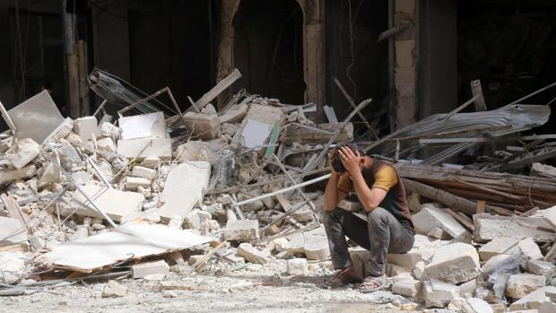 Un hombre, desolado entre los destrozos de los edificios tras el ataque aéreo del gobierno sirio en Alepo