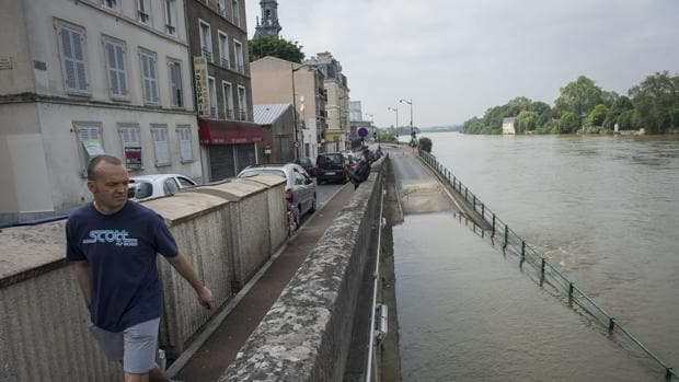 Un hombre camina junto al río Essonne, desbordado tras las fuertes lluvias en la localidad de Corbeil-Essonnes, cerca de París