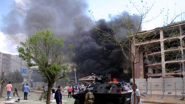 Ciudadanos junto a la comisaría de policía de Midyat mientras el humo asciende después de la explosión