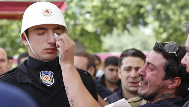 El familiar de una de las víctimas del atentado de esta semana en Estambul contra un autobús policial, seca las lágrimas de uno de sus compañeros durante su funeral en la mezquita de Fatih