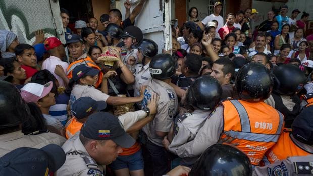 La Policía Nacional Bolivariana contiene a un grupo de personas que trata de entrar en un supermercado donde venden dos kilos de pasta por persona, este viernes en El Valle (Caracas)