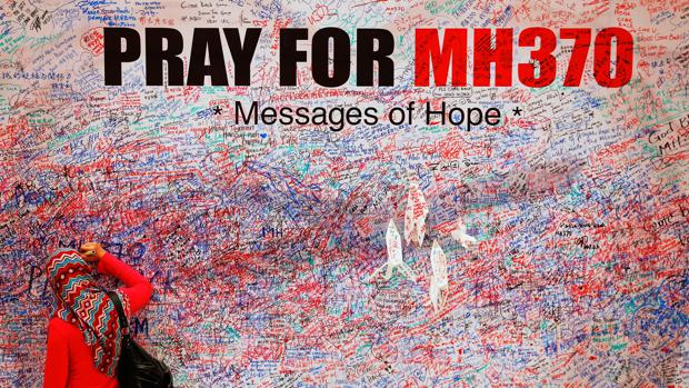 Una mujer escribe un mensaje esperanzador en un muro en honor a los pasajeros del avión MH370 desaparecido en 2014