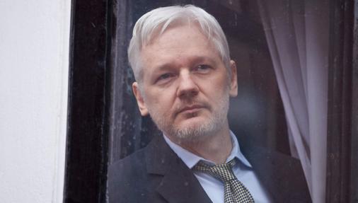 Assange asomándose al exterior desde la embajada de Ecuador en Londres