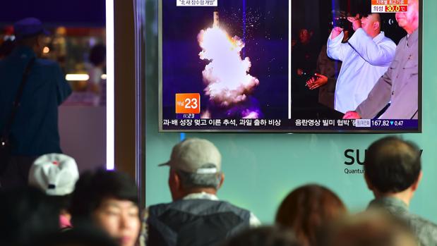 Varias personas ven a través de la televisión el lanzamiento de un nuevo misil desde un submarino en Corea del Norte