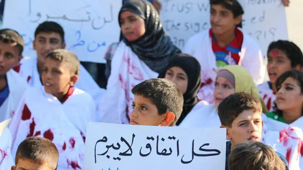Un grupo de niños de un barrio de Alepo controlado por los rebeldes pide la entrada de ayuda
