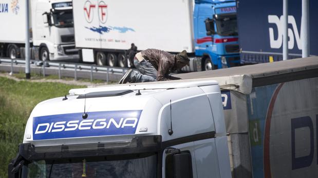 Un inmigrante se encarama a un camión que se dirige al túnel del Canal de la Mancha en dirección al Reino Unido en el puerto de Calais el 25 de junio de 2015