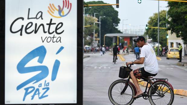 Un hombre pasa con su bicicleta cerca de un cartel a favor del «sí» a los acuerdos de paz, en Cartagena de Indias