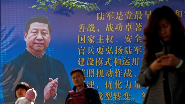 La gente camina delante de un póster del presidente chino, Xi Jinping
