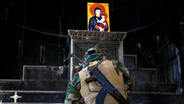 Un soldado iraquí enciende una vela en una iglesia recuperada de manos de Daesh en Qaraqosh