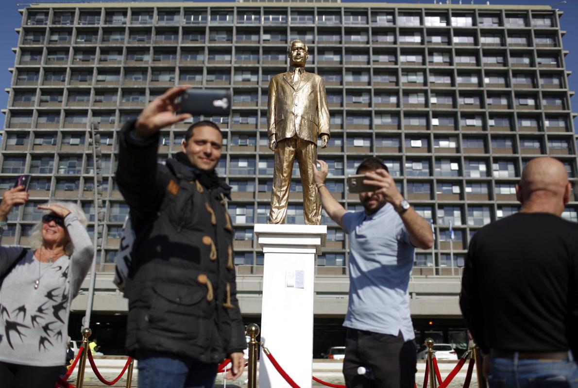 Un grupo de personas se acerca para ver una estatua dorada que representa al primer ministro israelí, Benjamín Netanyahu,