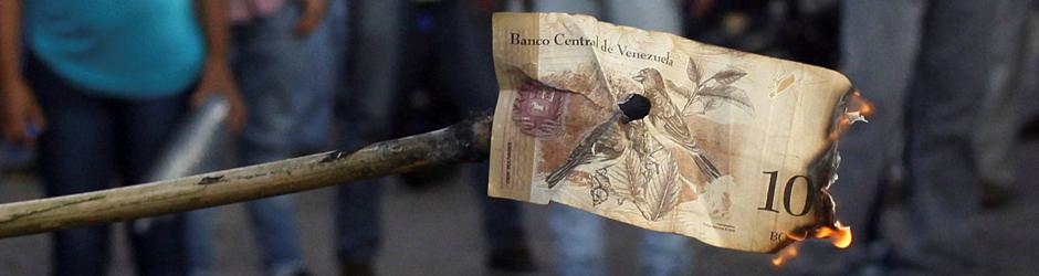Unos venezolanos queman un billete de cien bolívares, durante una protesta en El Pinal