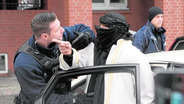 Un agente de policía alemán interroga a un hombre con el rostro tapado antes de subirse en un taxi frente a una mezquita en la calle Perleberger en Berlín (Alemania)