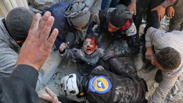 Los voluntarios de la defensa civil de Siria, conocidos como los Cascos Blancos, rescatan a un niño de los escombros tras un atentado con bomba en el barrio Bab al-Nairab de la ciudad de Alepo, en el norte de Siria, el 24 de noviembre de 2016