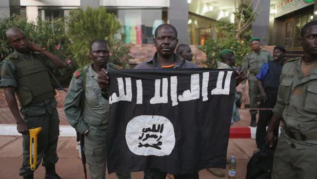 Soldados malienses muestran una bandera arrebatada a los terroristas que asaltaron un hotel en Bamako