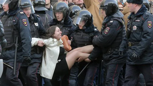 Policías antidisturbios rusos detienen a una manifestante durante las protetas convocadas por la oposición en el centro de Moscú