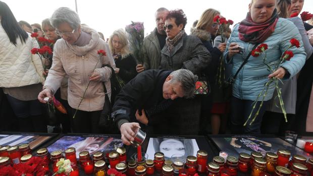 Varias personas depositan velas sobre el retrato de Malyukova Ksenia de 18 años, una de las víctimas del atentado en el metro de San Petersburgo