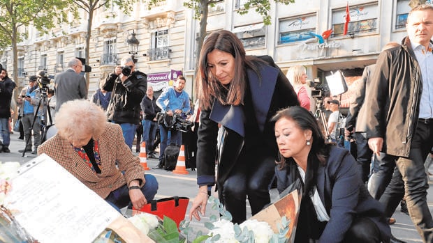 La alcaldesa de París, en el centro, deposita flores en el lugar donde fue asesinado el policia