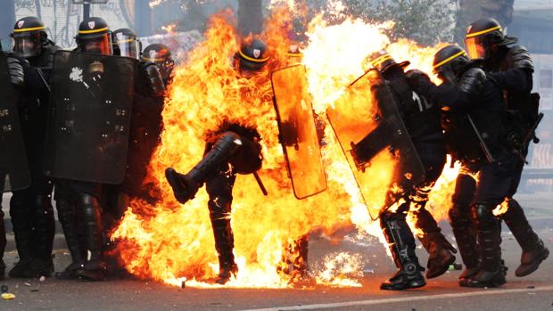 Policías franceses antidisturbios envueltos en llamas durante los enfrentamiento de París por el Primero de Mayo