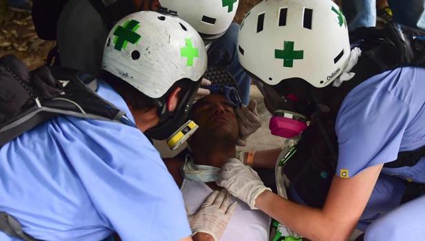 Un manifestante es asistido tras resultar herido en los choques entre la Policía antidisturbios y opositores en la Universidad Central de Venezuela, este jueves en Caracas
