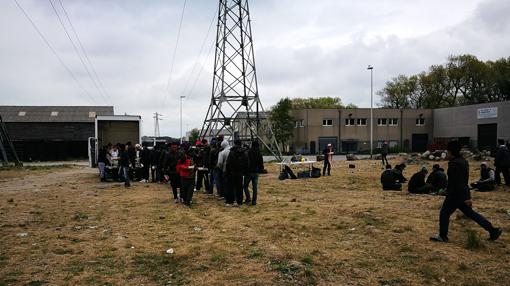 Descampado próximo al antiguo campo de La Jungla donde varios voluntarios reparten comida entre los inmigrante