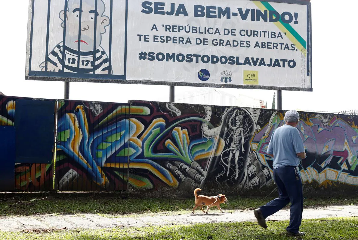 Un hombre pasa por delante de un cartel que refleja a Lula en la cárcel