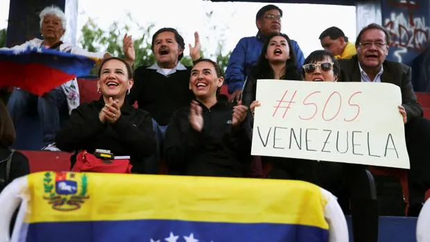 Ciudadanos venezolanos secundan un cartel que dice «SOS Venezuela»