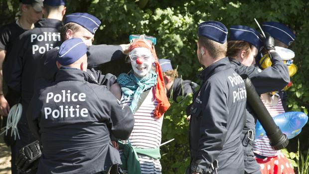Un manifestante vestido de payaso es detenido por la policía belga
