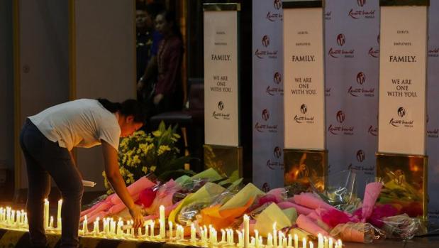 Una filipina deposita flores y velas en el hotel Resorts World Manila, asaltado por un hombre el jueves por la noche