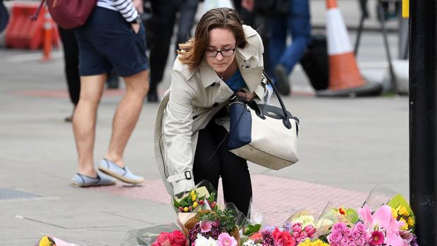 Una mujer deposita flores en una calle del Borough Market