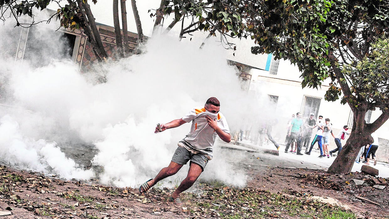 Un manifestante se protege del gas lacrimógeno lanzado por las Policía marroquí