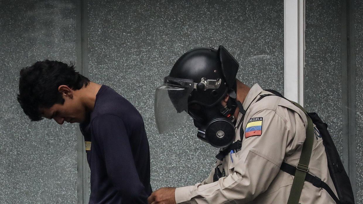 Agentes de la Policía Nacional Bolivariana detienen a unmanifestante durante una marcha hacia la sede del Poder Electoral