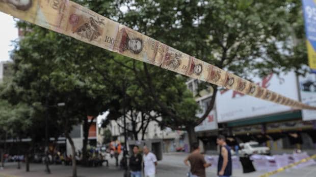 Manifestantes bloquean una calle de Caracas con cintas hechas de monedas y billetes