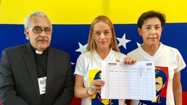 La esposa y la madre de Leopoldo López muestran el documento que da fe del voto del opositor, gracias a la mediación del rector S. J. Virtuoso (a la izquierda)