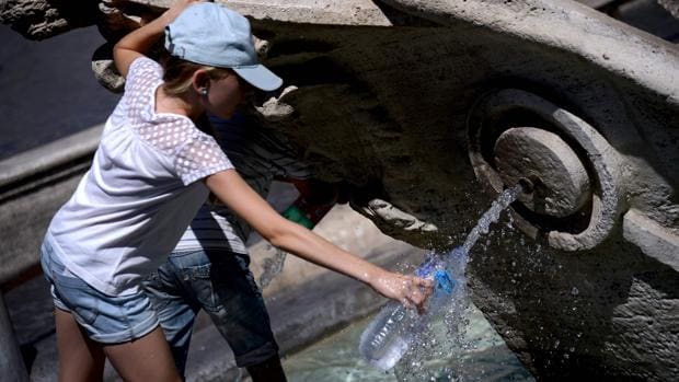 Una persona llena una botella de agua de la fuente de la Piazza di Spagna de Roma