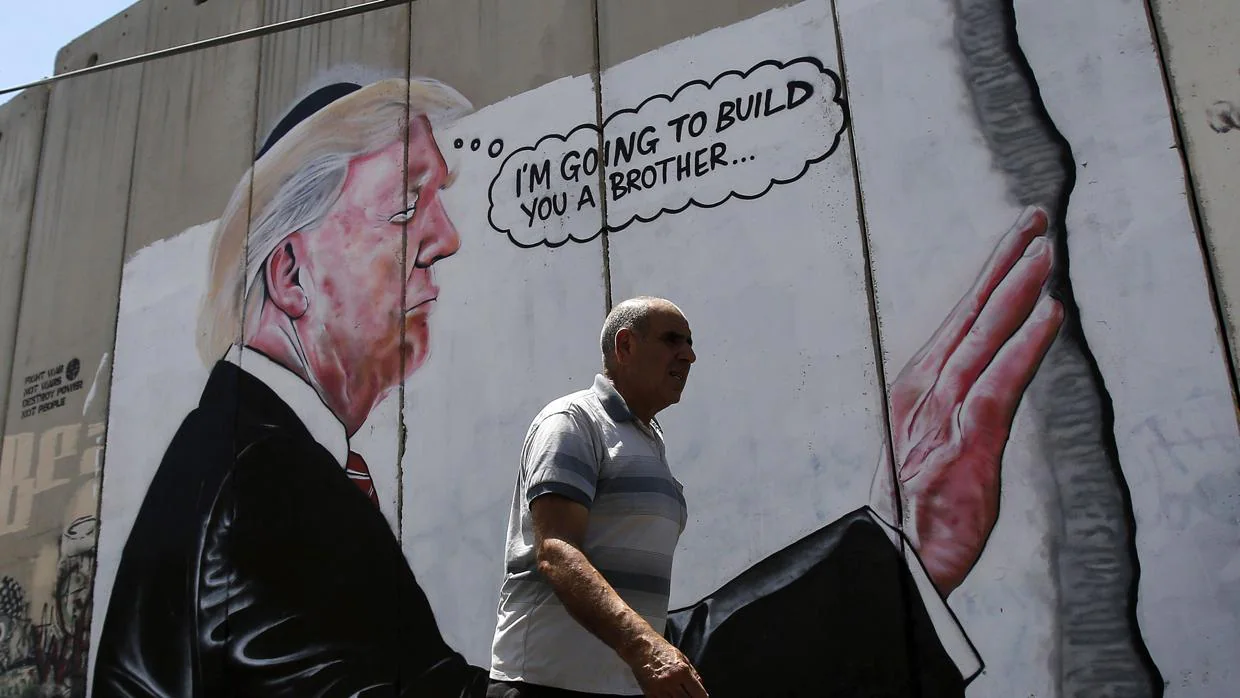Un hombre pasa por delante del graffiti del presidente de los Estados Unidos, Donald Trump, en el muro de Belén