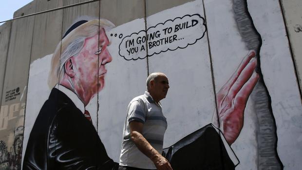 La pintada en un muro de separación israelí que caricaturiza a Trump y su plan de muro