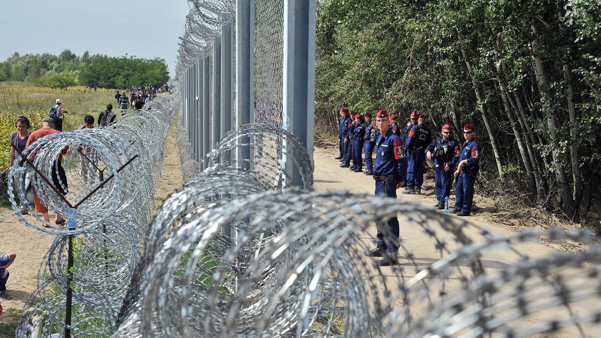 Un grupo de refugiados pasa frente al muro levantado por Hungría para impedir la llegada de migrantes