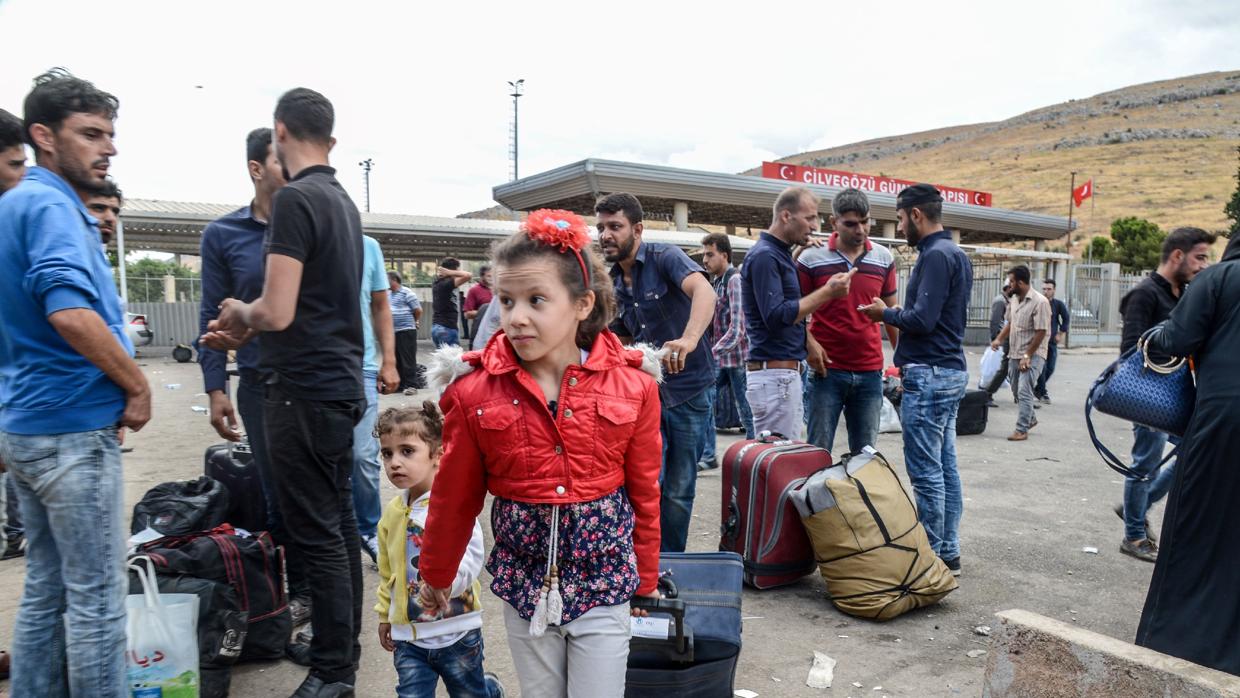 Varias familias sirias se llevan sus pertenencias mientras cruzan la puerta fronteriza al lado turco el 9 de octubre de 2017 en el distrito de Reyhanli en Hatay