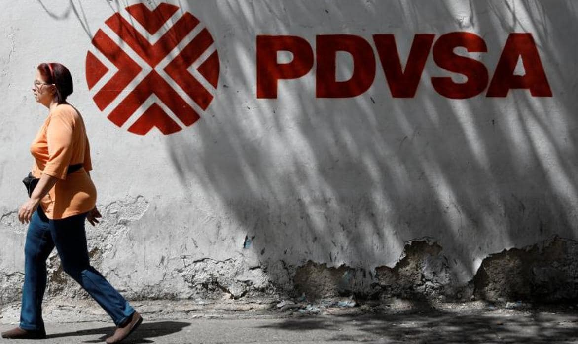Una mujer pasa junto a un muro con el logo de la petrolera estatal Pdvsa, en Caracas