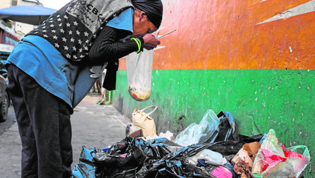 Una mujer hurga en la basura en una calle de Caracas