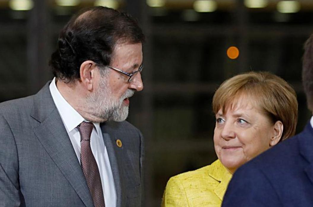 Mariano Rajoy conversa con Angela Merkel, durante la foto de familia en la cumbre de la UE, este jueves en Bruselas