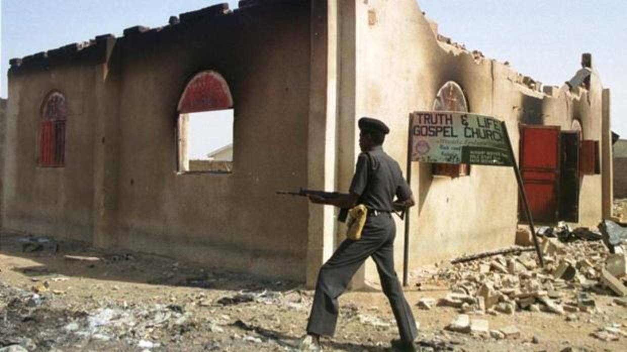 Un policía nigeriano pasa frente a una iglesia quemada por grupos rebeldes musulmanes el pasado mes de febrero