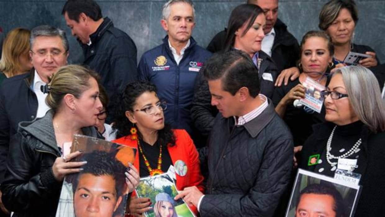 El presidente Enrique Peña Nieto con familiares de desaparecidos, el pasado mes de octubre tras aprobarse la Ley de Desaparicón Forzada. A la derecha, Yolanda Morán con la foto de su hijo Dan Jeremeel