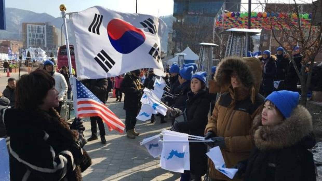 Con la bandera surcoreana (a la izquierda), los detractores de Kim Jong-un se manifiestan ante quienes piden la reunificación en los alrededores del Estadio Olímpico de PyeongChang
