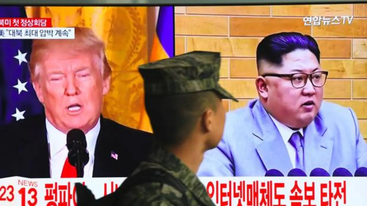 Un soldado surcoreano camina ante la imagen de Trump y Kim Jong-un